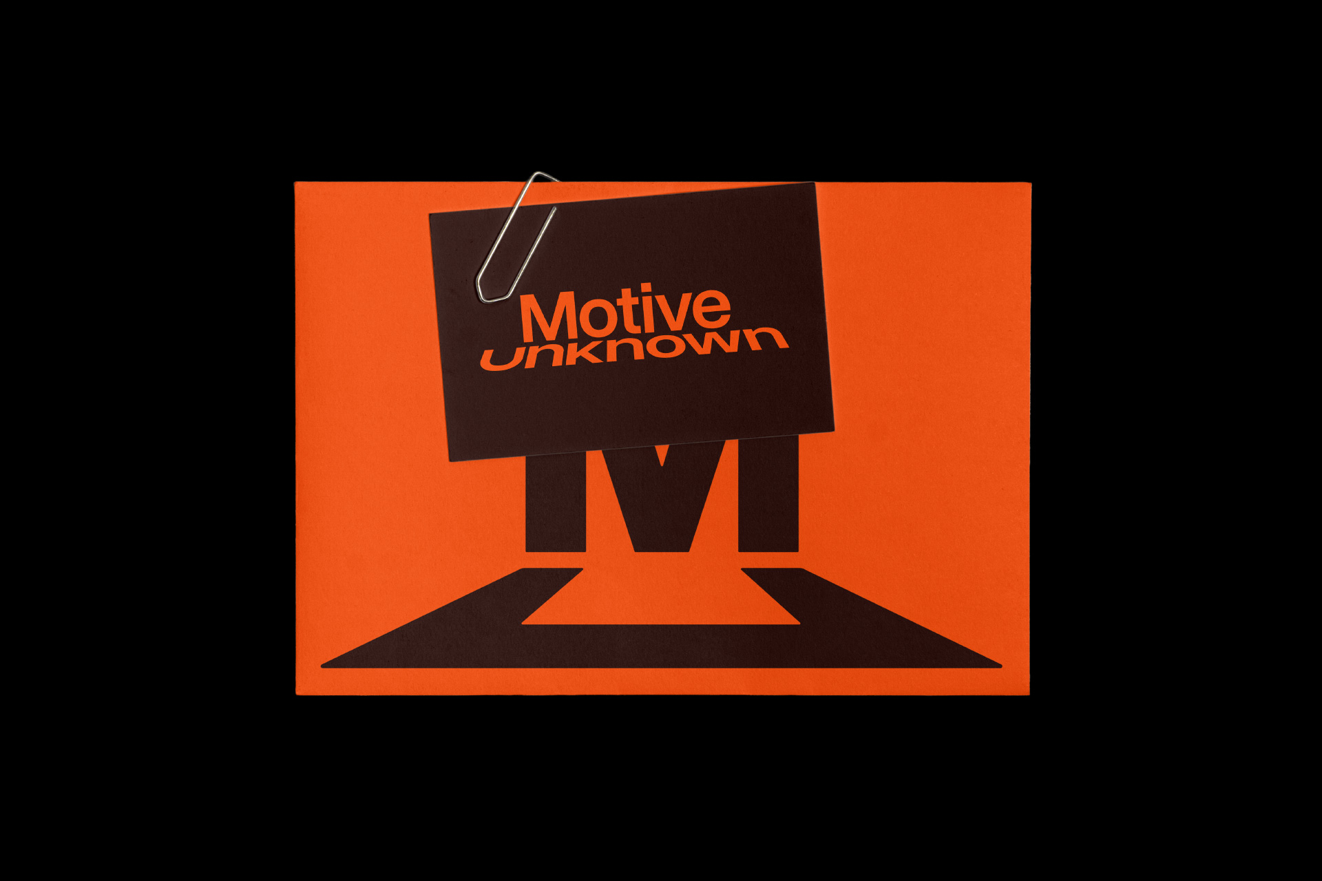 A dark card with the Motive Unknown wordmark, clipped to an orange envelope printed with the mark